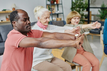 Group of senior people doing morning exercises together in the room