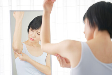 Fototapeta na wymiar 鏡の前で二の腕の贅肉を摘む女性