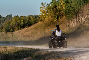 a sexy girl with long dark hair rides an ATV off-road; the girl feels drive and adrenaline; extreme recreation outside the city; Quad bike rental