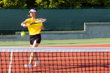 Professional equipped female tennis player beating hard the tennis ball with racquet.