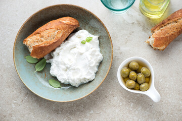 Plate with italian ricotta cheese on a beige stone background, horizontal shot, view from above