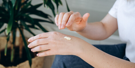Beautiful woman applies hand cream to her hands, skin moisturizing care and manicure