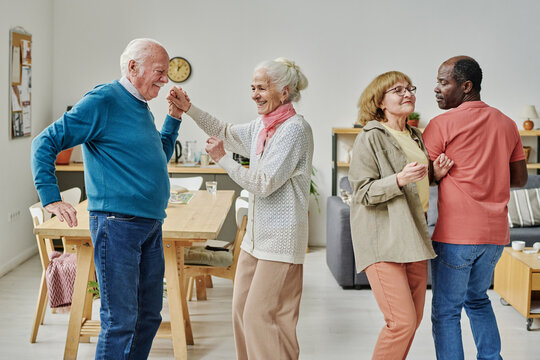 Group of happy elderly people dancing together at party in nursing home