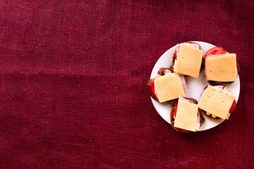 Open sandwich with rye bread, tomatoes, ham and cheese on white plate. Breakfast or brunch concept. Top view, copy space