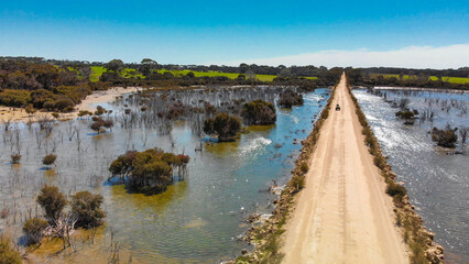 Kangaroo Island unpaved road along lake and trees, aerial view from drone - Australia