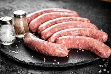 Raw sausages on a stone board with spices. 