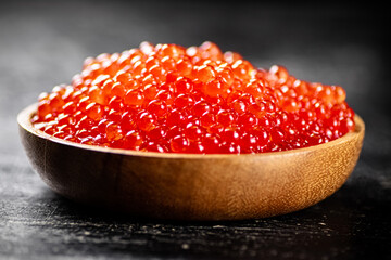 Red caviar in a wooden plate. 