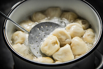 Dumplings are taken out of the pan with a skimmer. 