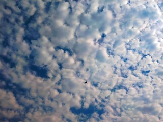 The passenger airplane is flying far away in the blue sky and white clouds. Aircraft in the air. International passenger air transportation. 
