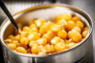 An open can of canned corn with a spoon. 