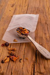 Inox tea spoon inside a tea bag with fruity tea placed on vintage old oak. 