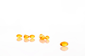 One orange jelly pill in foreground on white reflective glass with many others orange pills blurred in the background. 