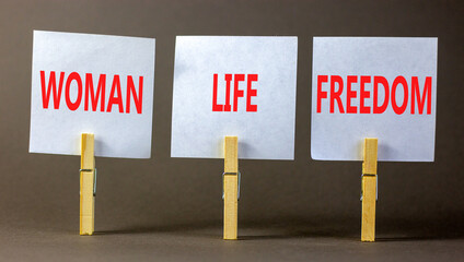 Woman life freedom symbol. Concept words Woman Life Freedom on white paper on clothespin on a beautiful grey table grey background. Social issue woman life freedom concept. Copy space.