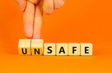 Safe or unsafe symbol. Concept word Safe Unsafe on wooden cubes. Businessman hand. Beautiful orange table orange background. Business safe or unsafe concept. Copy space.