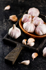 Garlic on a wooden plate on a cutting board. 