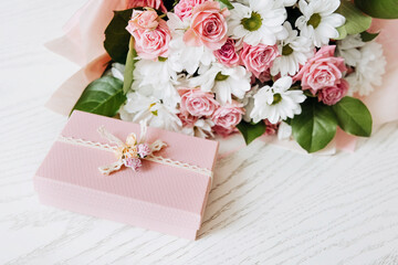 Beautiful bouquet of rose and chrysanthemums flowers and pink gift box on white table background. Gift for holiday, birthday, Wedding, Mother's Day, Valentine's day, Women's Day. Floral arrangement.