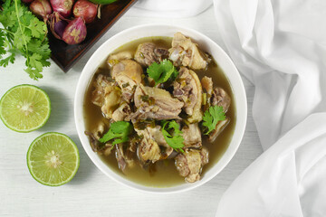 Homemade chicken soup with galangal,  lemon grass in white bowl.