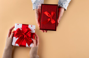 The couple exchange gifts for Valentine's Day. Woman givin her partner a wrapped gift. Hands giving gifts close-up. Gifts for the Valentine's Day.