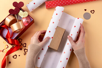 Young woman packing gift for her boyfriend. Close up of female hands packing gift for boyfriend....