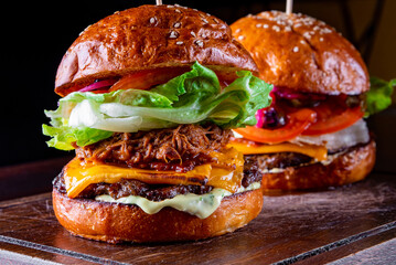 two barbecue pulled beef burgers with vegetables on dark background