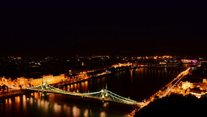 Fototapeta na wymiar the Liberty bridge in Budapest. aerial night view. brightly illuminated steel structure. reflection on water. tourism and travel concept. transportation and design. evening lights over the Danube.