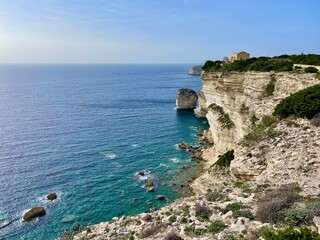 Rocky cliffs of Accore coast near Bonifacio (Corsica, France) view, stack of the Grain of Sand ("U Diu Grossu" in Corsican, a big rock in the blue sea), from hiking path in the top vegetation