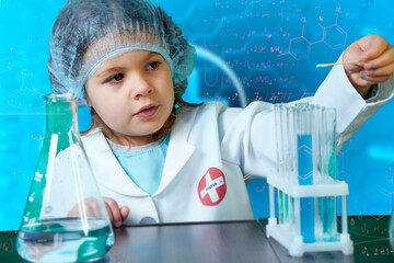 Little kid doing experiments with blue liquid. Cute child wants to become a doctor. Pretty child in...