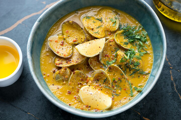 Bowl of chickpea cream-soup with littleneck clams, middle closeup on a dark-olive marble background, horizontal shot