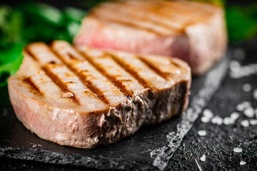Grilled tuna on a stone board with parsley and salt. 