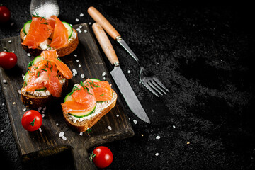 Sandwich with pieces of salmon on a cutting board. 