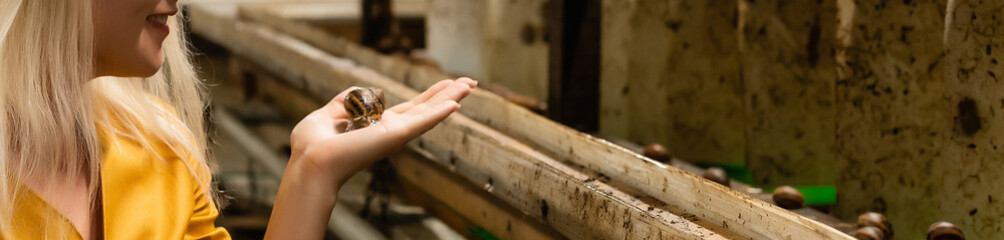 Close-up of snails on women's hand in the hothouse of a farm for growing snails.