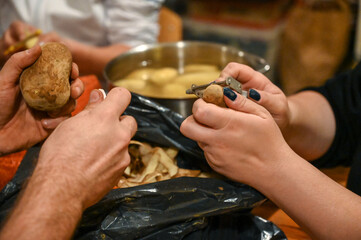 Man and woman peeling potatoes with knifes. Preparing dinner. 