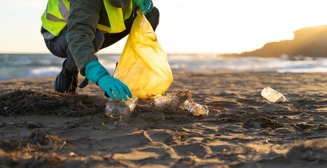 Volunteer collecting plastic from beach sand. copy space right with sunset. Recycling concept,...