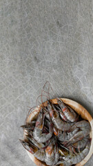 Raw black tiger prawns in wooden plate on a concrete background, top view, mock up, copy space