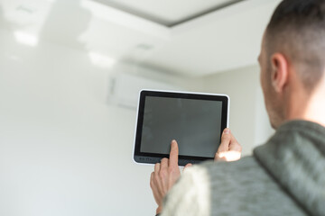 Smart home control on tablet. Interior of living room in the background.
