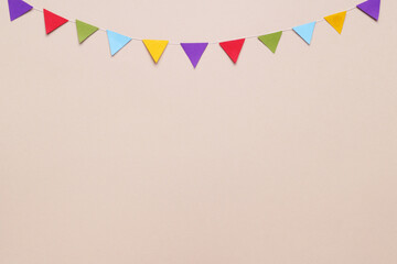 Colorful bunting flags on beige background, flat lay. Space for text