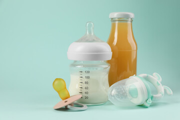 Milk, juice, pacifier and nibbler on light blue background. Baby nutrition