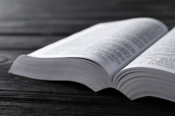 Open Bible on black wooden table, closeup. Christian religious book