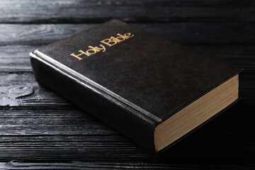 Bible with dark cover on black wooden table. Christian religious book