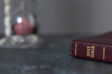 Holy bible book with an hourglass in the background. Copy space for text. Christian biblical...
