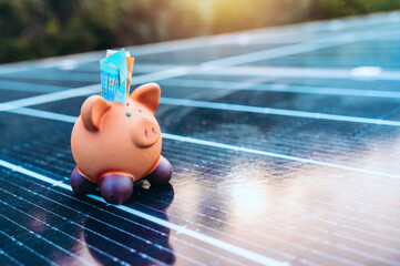 Piggybank on solar panel concept of money saved by using clean energy