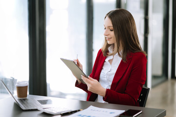 Asian businesswoman working in the office with working notepad, tablet and laptop documents .