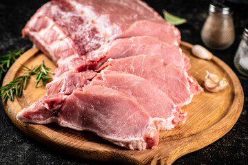 Fresh raw pork on a cutting board with rosemary.