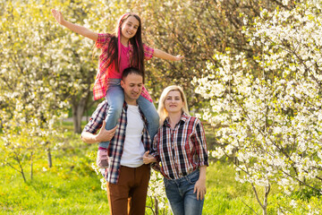 Fototapeta premium Happy family spending good time together in spring in a flowering garden