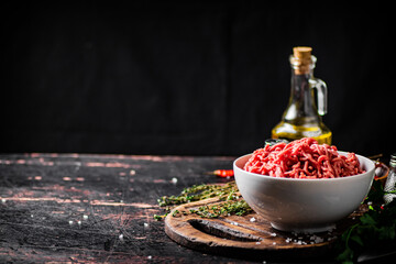 Minced meat in a bowl on a cutting board with sprigs of thyme. 