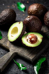 Cut avocado with leaves on a cutting board. 