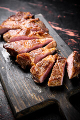 Slices of grilled steak pork on a wooden cutting board. 