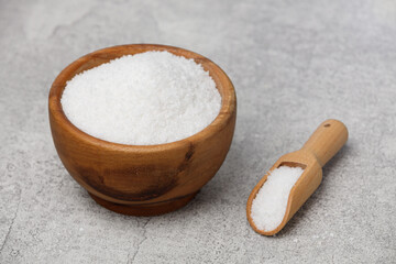 Coarse salt in a wooden bowl on a gray kitchen table.