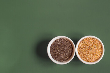 Top view of whole chia and flax seeds in small round white ceramic bowls, side by side, on a studio background with copy space. Healthy seeds to eat.