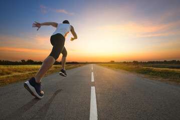 Fototapeta na wymiar A man running on country road with sun dawn sky background...